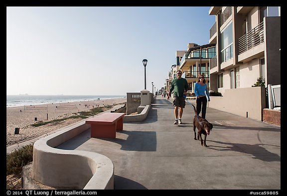 Couple walking dog on beachfront promenade, Manhattan Beach. Los Angeles, California, USA (color)