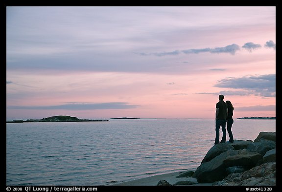Couple standing on rock and Atlantic Ocean at sunset, Westbrook. Connecticut, USA