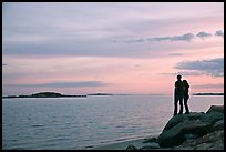 Couple standing on rock and Atlantic Ocean at sunset, Westbrook. Connecticut, USA