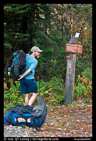 Backpacker shouldering pack at trailhead. Maine, USA