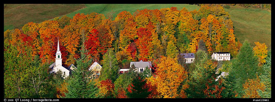 White-steppled church and houses amongst trees in fall foliage. Vermont, New England, USA