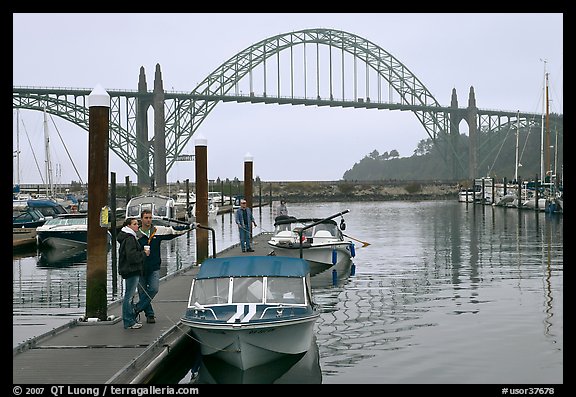 Couple holds  small boat on pier, Newport Marina. Newport, Oregon, USA (color)