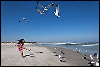 Beach with flying seagulls and girl, Jetty Park. Cape Canaveral, Florida, USA