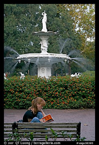 Woman sitting on bench with book in front of Forsyth Park Fountain. Savannah, Georgia, USA (color)