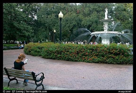 Forsyth Park Fountain with woman sitting on bench with book. Savannah, Georgia, USA