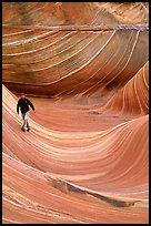 Hiker balances himself in the Wave. Vermilion Cliffs National Monument, Arizona, USA