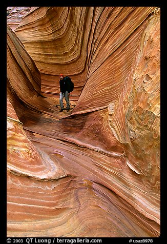 Hiker with backpack on a side formation of the Wave. Coyote Buttes, Vermilion cliffs National Monument, Arizona, USA
