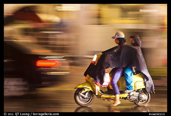 Women riding scooter in the rain. Ho Chi Minh City, Vietnam