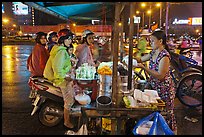 Women riding motorbikes buy sweet rice. Ho Chi Minh City, Vietnam (color)
