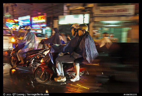 Motorcyle riders at night, dressed for the rain. Ho Chi Minh City, Vietnam (color)