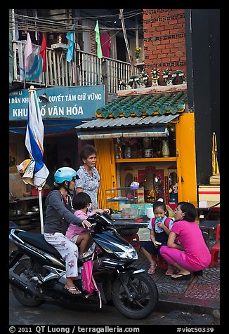 Neighborhood chat in front of street altar. Ho Chi Minh City, Vietnam