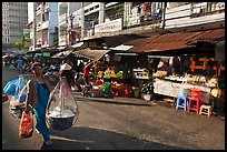 Woman carrying goods on street market. Ho Chi Minh City, Vietnam