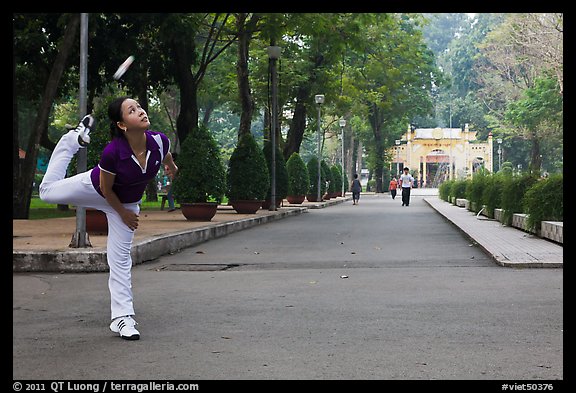 Woman plays badminton using feet (footbag), Tao Dan Park. Ho Chi Minh City, Vietnam (color)