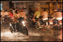 Man riding motorbike on flooded street seen against riders going in opposite direction. Ho Chi Minh City, Vietnam (color)