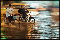 Bicyle and motorbike riders on monsoon-flooded street. Ho Chi Minh City, Vietnam