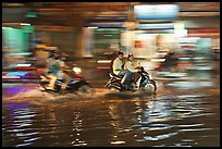 Motorcycles riding through the water on street with motion. Ho Chi Minh City, Vietnam (color)