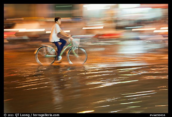 Night Bicyclist, water, and motion light streaks. Ho Chi Minh City, Vietnam
