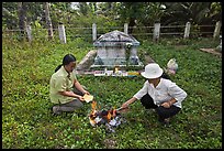 Women burning notes as offering in cemetery, Ben Tre. Mekong Delta, Vietnam ( color)