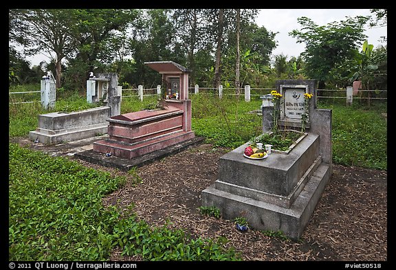 Graves in family cemetery with fresh offerings. Ben Tre, Vietnam (color)