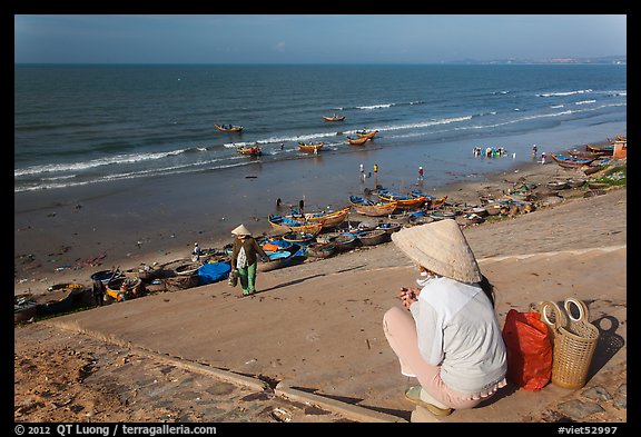 Woman on stairs overlooking beach with fishing boats. Mui Ne, Vietnam