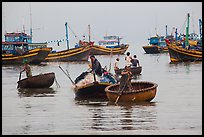 Men use round woven boats to disembark from fishing boats. Mui Ne, Vietnam (color)