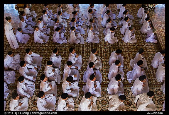 Worshippers dressed in white pray in neat rows in Cao Dai temple. Tay Ninh, Vietnam (color)