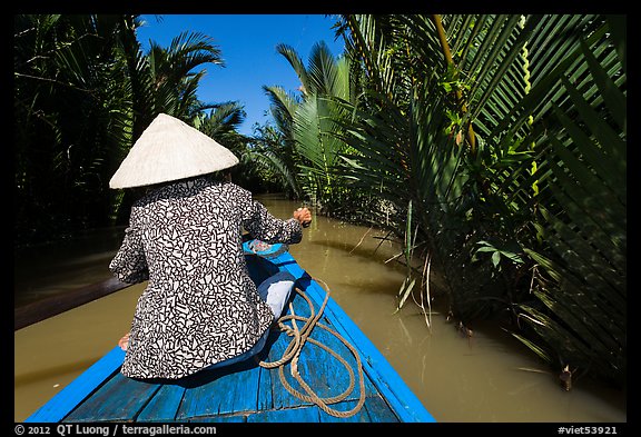 Woman rowing boat in canal lined up with vegetation, Phoenix Island. My Tho, Vietnam (color)