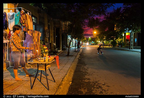 Woman tends to altar on street at dusk. Hoi An, Vietnam (color)