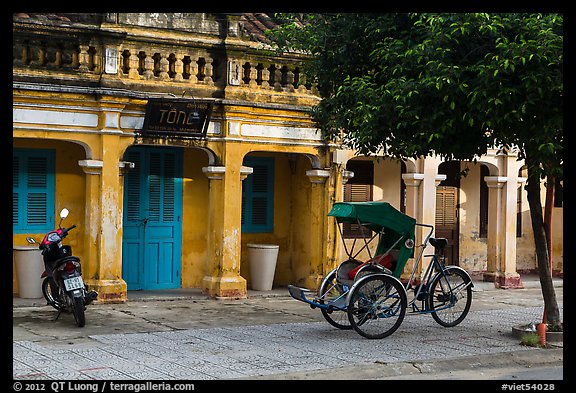 Motorcyle and cyclo in front of old townhouses. Hoi An, Vietnam