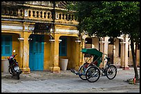 Motorcyle and cyclo in front of old townhouses. Hoi An, Vietnam ( color)