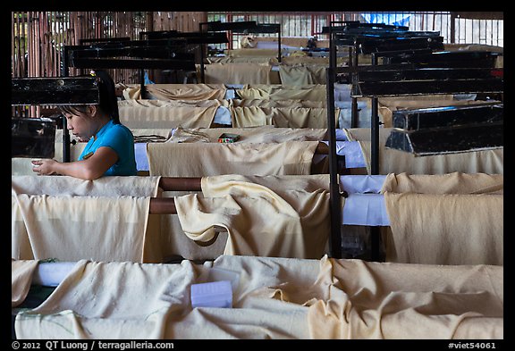 Woman takes pause at silk weaving workshop. Hoi An, Vietnam