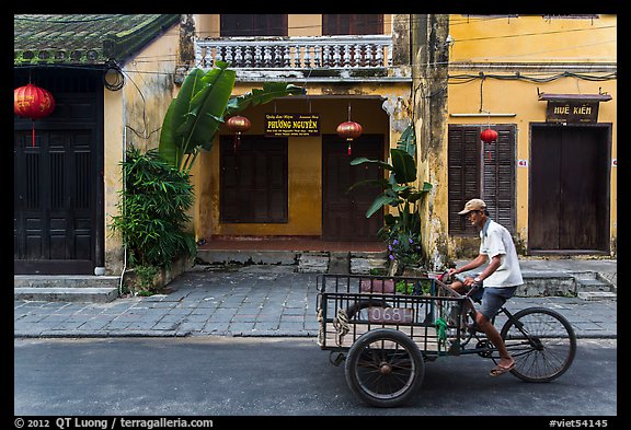 Man riding tricycle cart in front of old townhouses. Hoi An, Vietnam