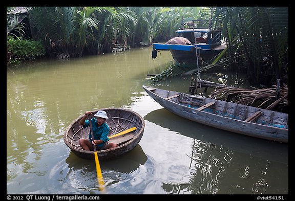 Man rows coracle boat in river channel. Hoi An, Vietnam