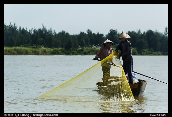 Fishermen standing in boat retrieving net, Thu Bon River. Hoi An, Vietnam (color)