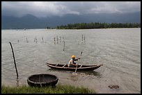 Fisherman rowing canoe in lagoon. Vietnam ( color)