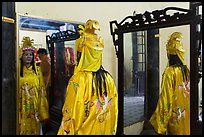 Woman in imperial dress checking herself in mirror, citadel. Hue, Vietnam (color)