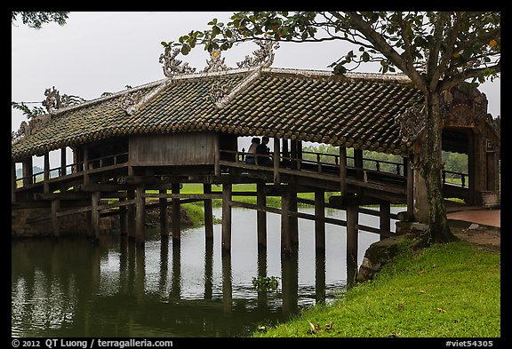 Friends sitting inside covered bridge, Thanh Toan. Hue, Vietnam