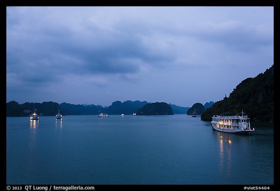View of bay with lights of anchored tour boats at dawn. Halong Bay, Vietnam