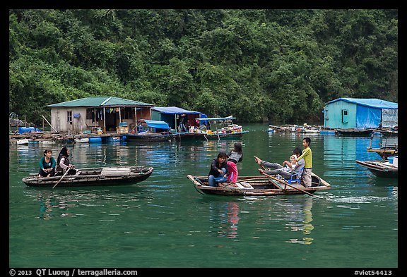 Villagers move between floating houses by rowboat. Halong Bay, Vietnam (color)