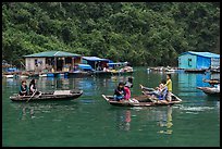 Villagers move between floating houses by rowboat. Halong Bay, Vietnam (color)