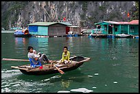 Man holding infant while rowing with feet, Vung Vieng village. Halong Bay, Vietnam ( color)