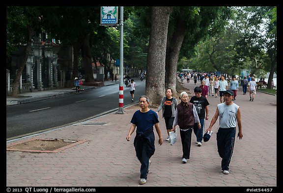 Numerous people walk counter-clockwise around Hoang Kiem Lake. Hanoi, Vietnam (color)