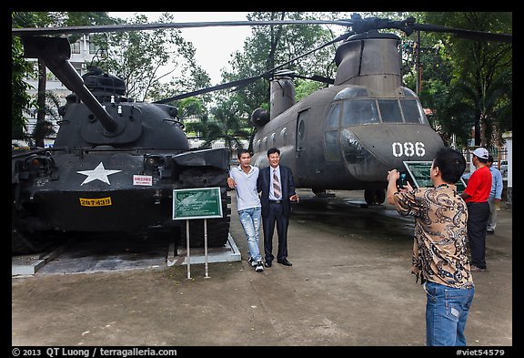 Tourists pose with tanks and helicopters, War Remnants Museum, district 3. Ho Chi Minh City, Vietnam (color)