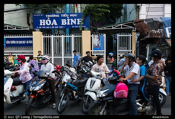 School entrance with parents waiting on motorbikes. Ho Chi Minh City, Vietnam (color)