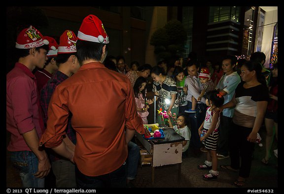 People gather around street hawker on Christmas eve. Ho Chi Minh City, Vietnam