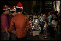 People gather around street hawker on Christmas eve. Ho Chi Minh City, Vietnam (color)