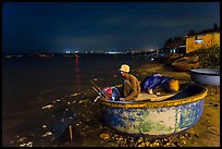 Man working on coracle boat at night. Mui Ne, Vietnam ( color)