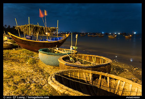 Coracle boats and fishing fleet at night. Mui Ne, Vietnam (color)