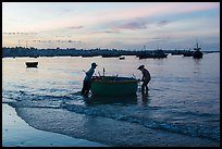 Fishermen pushing coracle boat at dawn. Mui Ne, Vietnam ( color)