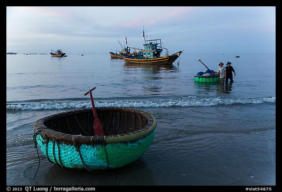 Coracle and fishing boats at dawn. Mui Ne, Vietnam